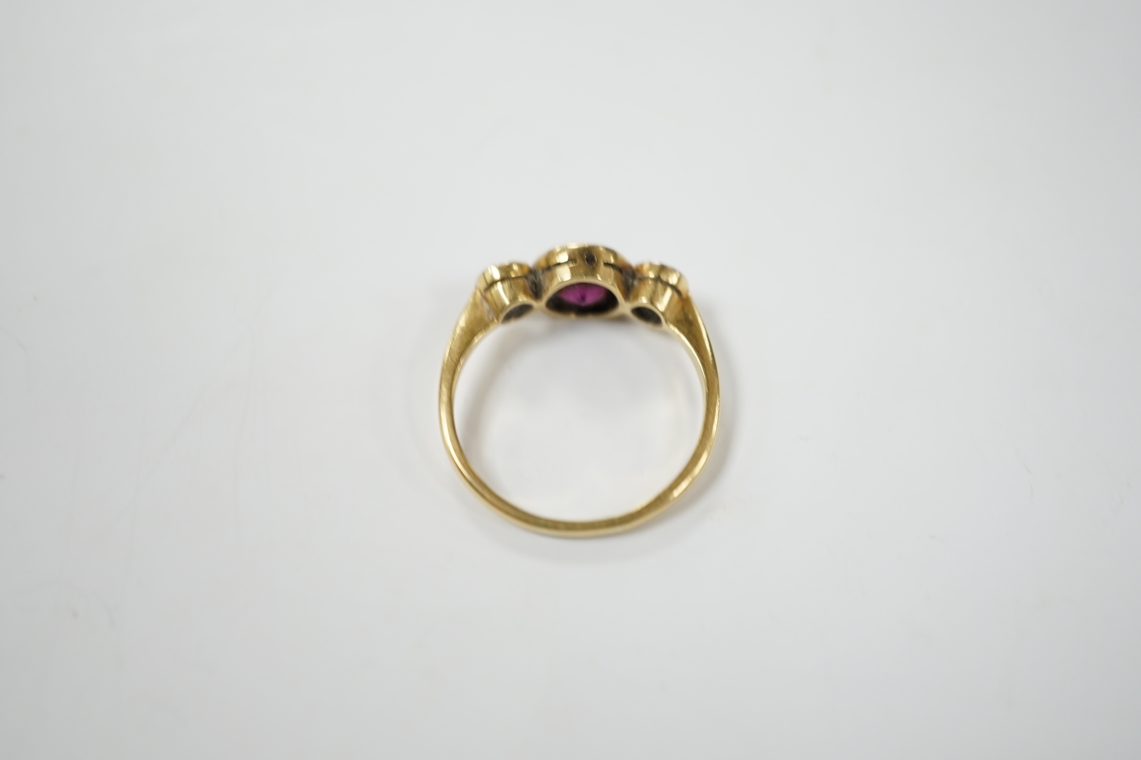 An early 20th century yellow metal and millegrain set single stone garnet and two stone diamond ring, size M, gross weight 2.8 grams.